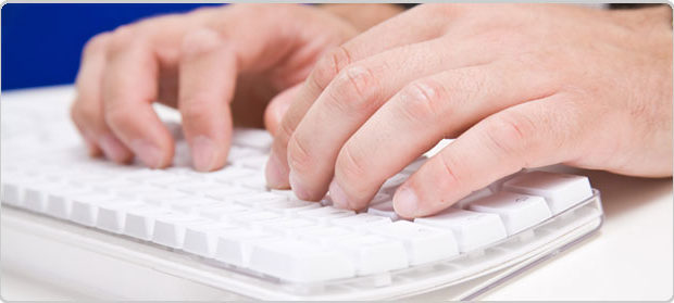 a hand typing on a white keyboard